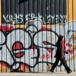 a person walking past a wall with graffiti on it