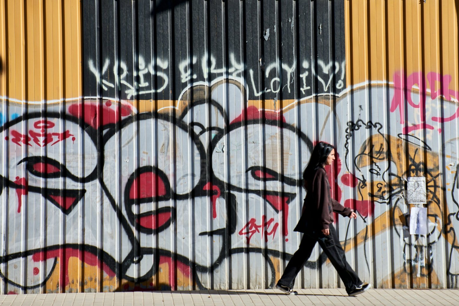 a person walking past a wall with graffiti on it